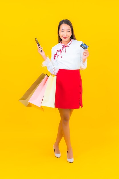 Portrait beautiful young asian woman with shopping bag and credit card on yellow