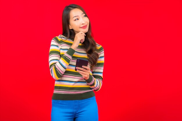 Portrait beautiful young asian woman with smart mobile phone on red wall