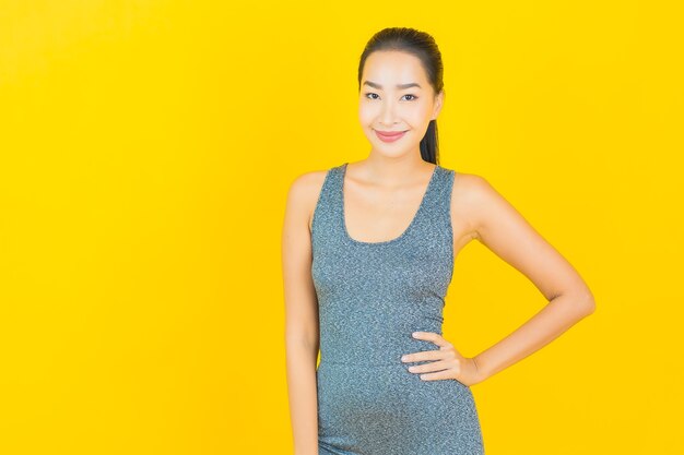 Portrait beautiful young asian woman with sportswear ready for exercise on yellow wall