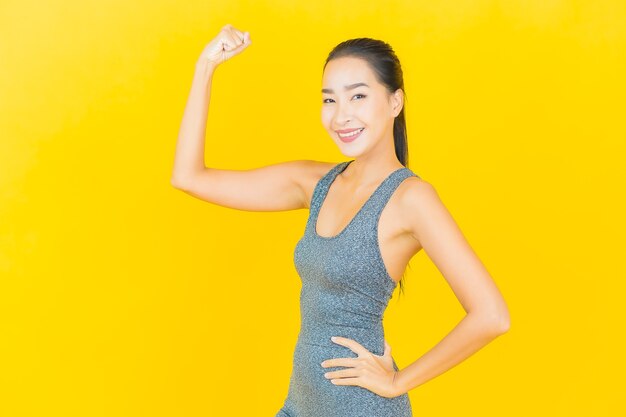 Portrait beautiful young asian woman with sportswear ready for exercise on yellow wall