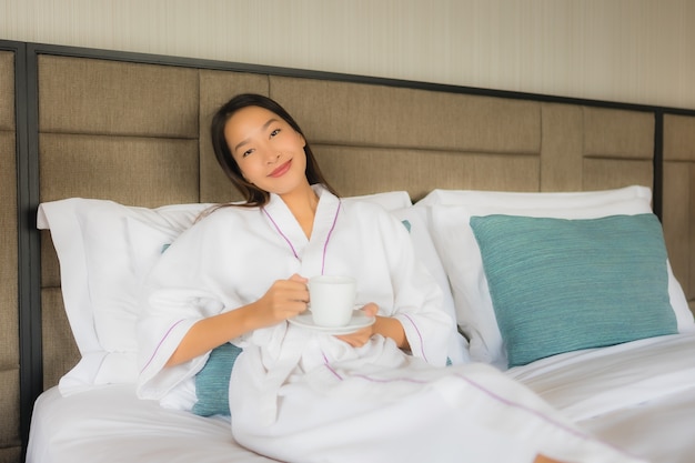 Portrait beautiful young asian women with coffee cup on bed