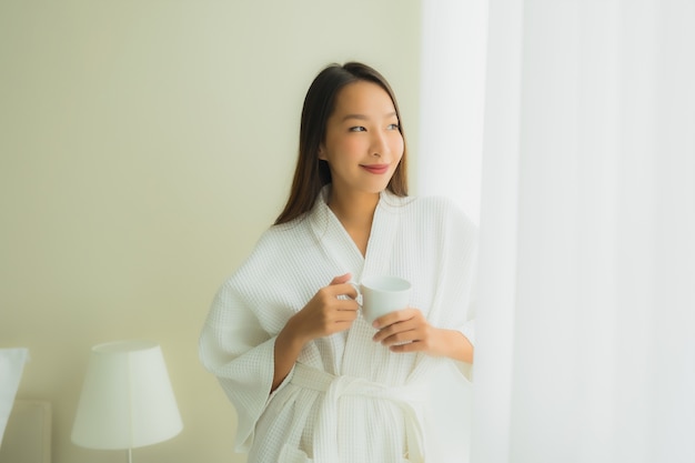 Portrait beautiful young asian women with coffee cup in bedroom