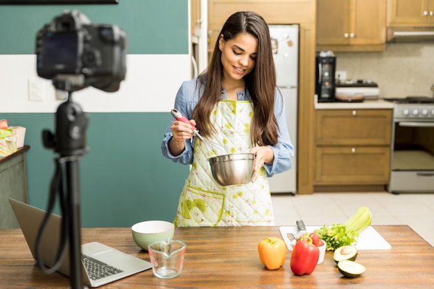 Portrait of a beautiful young food blogger preparing some food and recording a video at home