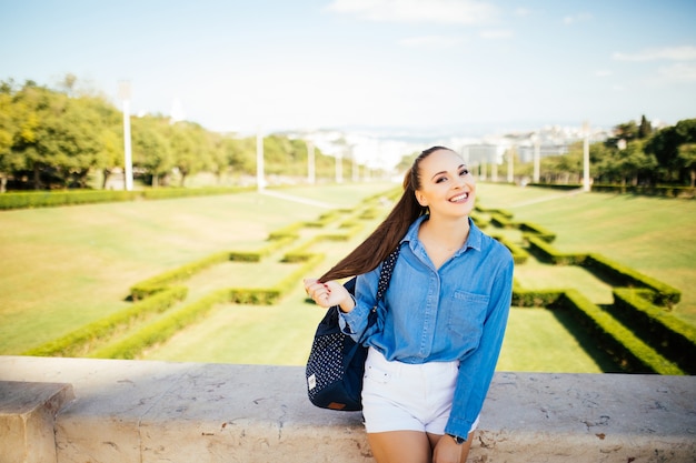 Portrait of a beautiful young smiling woman in green summer city park