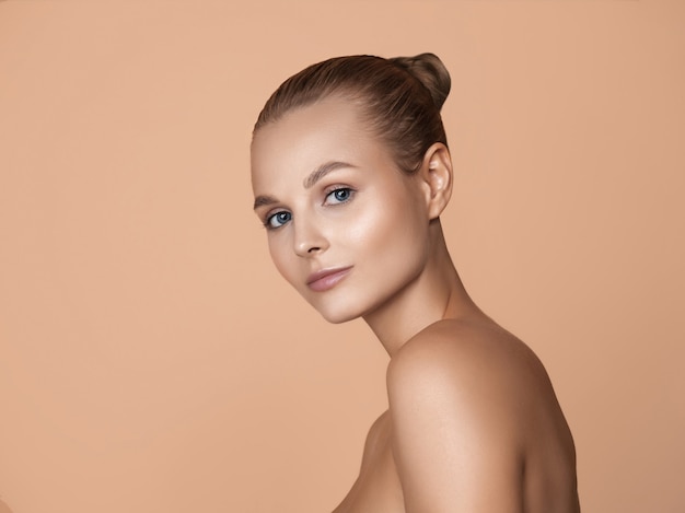 Free photo portrait of beautiful young woman on brown studio