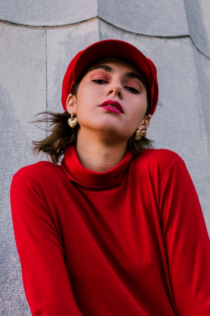 Free Photo portrait of a beautiful young woman in red cap and top standing in front of wall