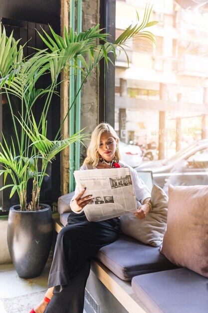 Portrait of a beautiful young woman sitting in caf� reading newspaper