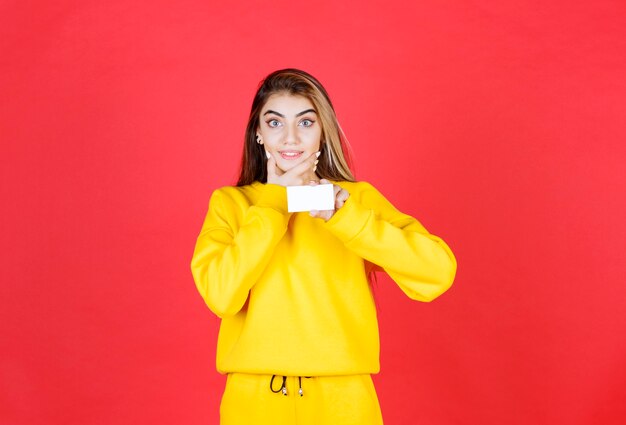 Portrait of beautiful young woman with blank business card standing