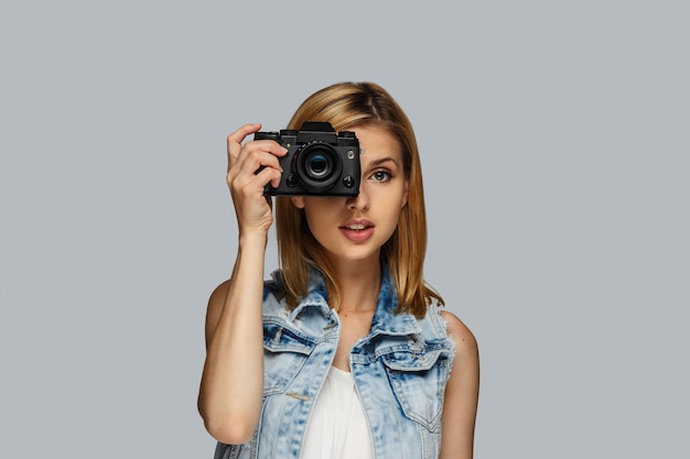 Free photo portrait of blond female photographer isolated on grey background.