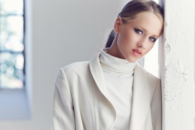 Portrait of blond female with blue eyes and in white clothes.