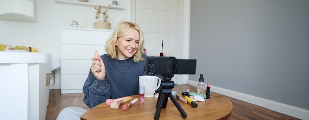 Portrait of blond smiling woman records a lifestyle blog vlogger or makeup artist recording video