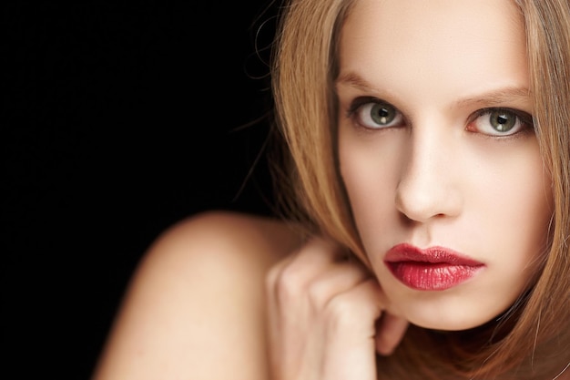 Portrait of blond woman with red lips isolated on black background.