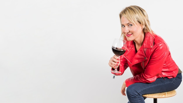 Free Photo portrait of a blonde mature woman holding red wine glass in hand isolated on white background