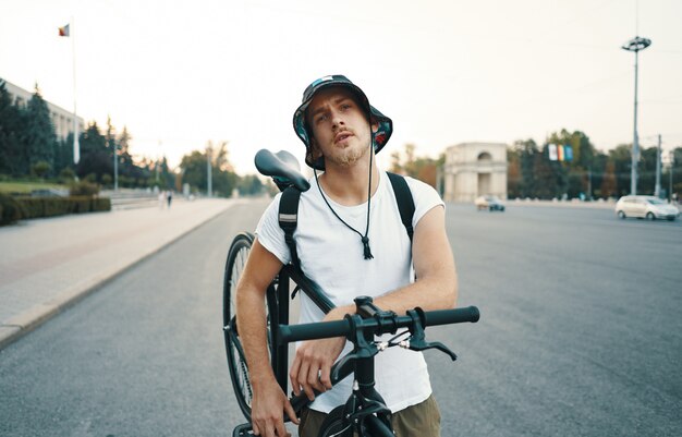 Portrait of a blonde white man in the city with a classic bike