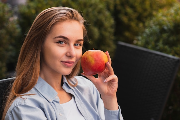 Free photo portrait of blonde woman holding a apple