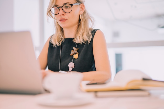 Portrait of a blonde young businesswoman looking at laptop in the office