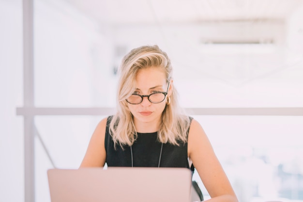 Portrait of blonde young businesswoman looking at laptop