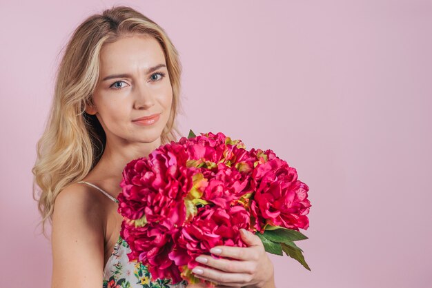 Portrait of blonde young woman holding flower bouquet in hands