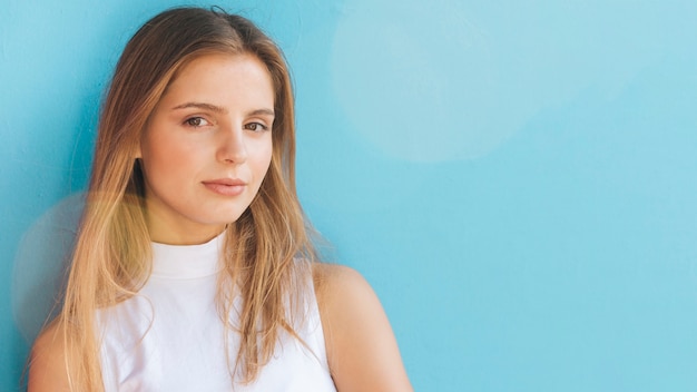 Free Photo portrait of a blonde young woman looking at camera against blue background