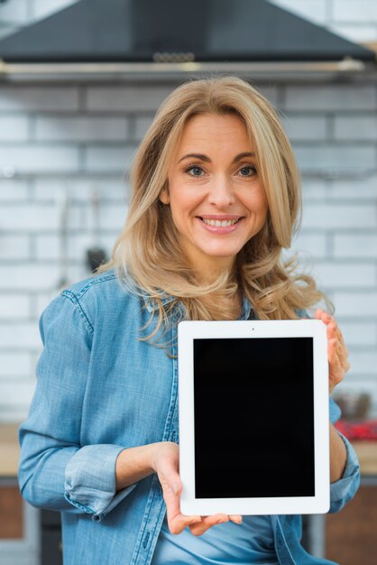 Portrait of a blonde young woman showing digital tablet