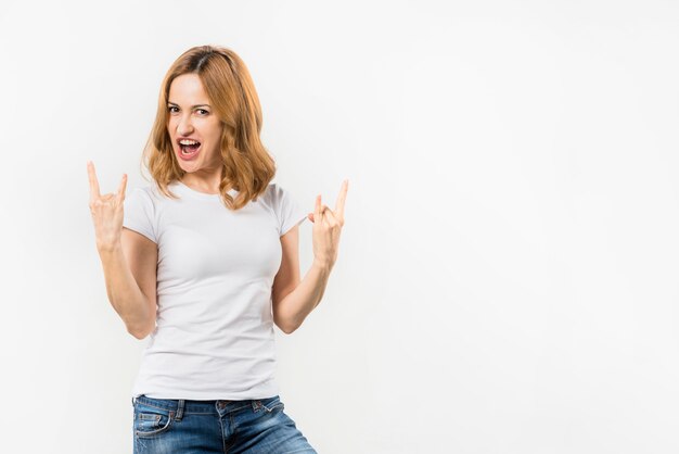 Portrait of a blonde young woman showing rock and roll gesture against white backdrop