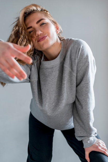 Free photo portrait of a blonde young woman standing against grey wall