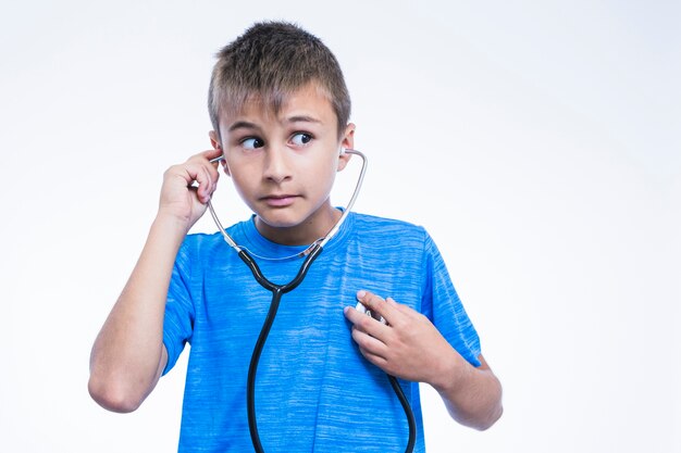 Portrait of a boy checking his heartbeat with stethoscope on white background