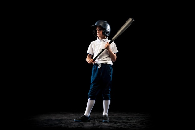 Free photo portrait of boy child baseball player in uniform training practising isolated over black studio background