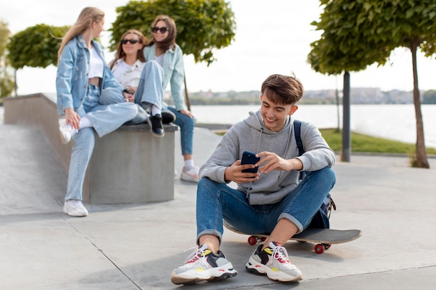 Portrait of boy holding a skateboard next to his friends