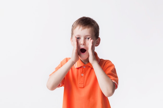 Portrait of boy screaming with mouth open standing near white wall