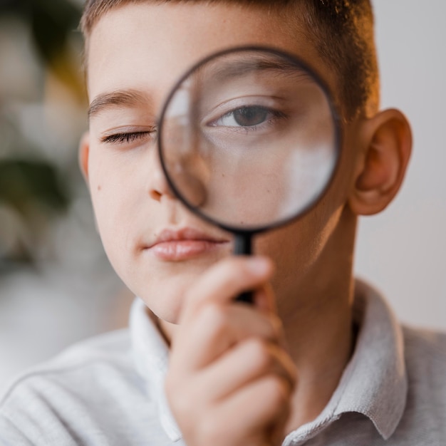 Portrait of boy using a magnifier in class