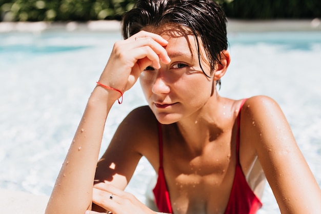 Free Photo portrait of brown-haired woman with tanned skin relaxing in pool.