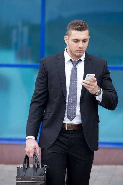 Portrait of business man looking at smartphone screen with focused expression