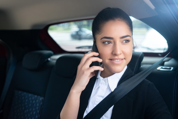 Portrait of business woman talking on phone on her way to work in a car. Business concept.