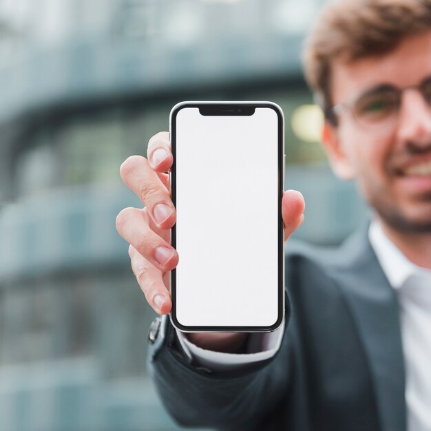 Portrait of a businessman showing white screen mobile phone toward camera