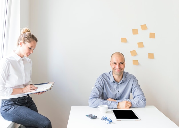 Free photo portrait of businessman sitting near the businesswoman sitting on window sill