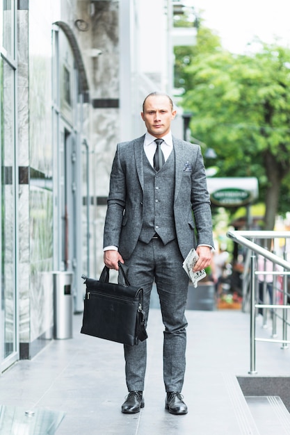 Portrait of a businessman with laptop bag and newspaper