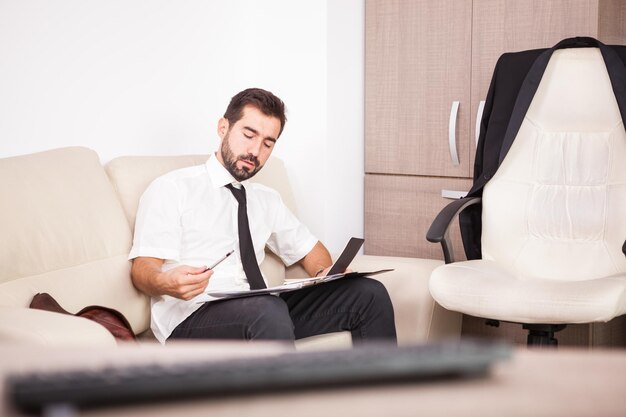 Portrait of Businessman working in the office on the couch putting long hours of work. Businessperson in professional environment