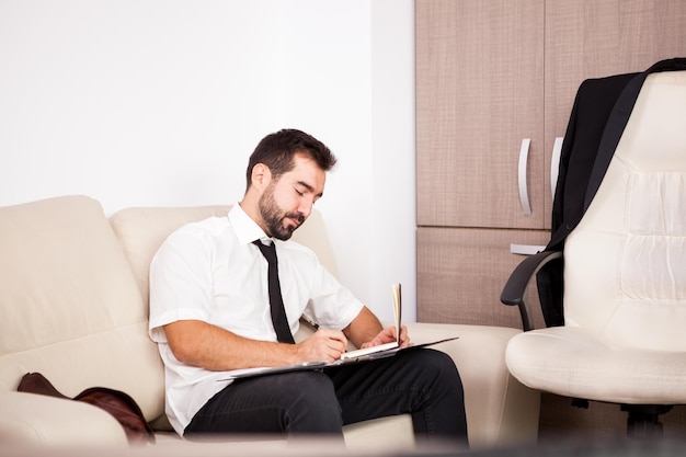 Free photo portrait of businessman working in the office on the couch putting long hours of work. businessperson in professional environment