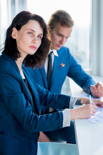 Portrait of a businesswoman sitting with her male colleague in office