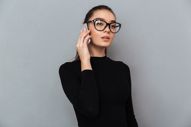 Portrait of a busy young woman in eyeglasses talking