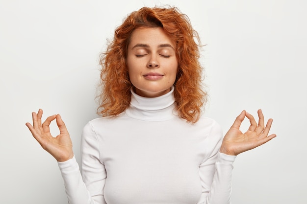 Free Photo portrait of calm relaxed beautiful female model practices yoga meditates with eyes shut