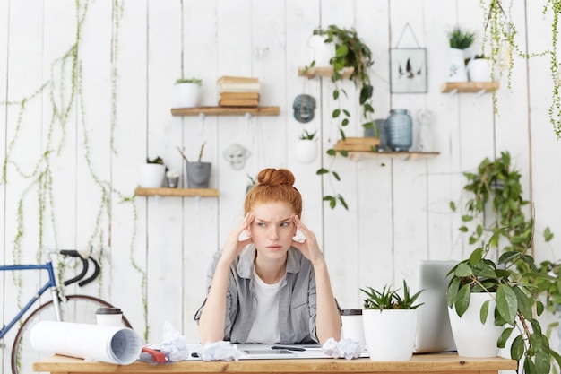 Free photo portrait of caucasian female architect sitting at her workplace over sketches