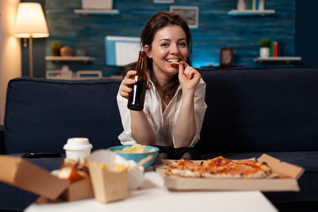 Portrait of caucasian female looking into camera holding beer bottle in hands