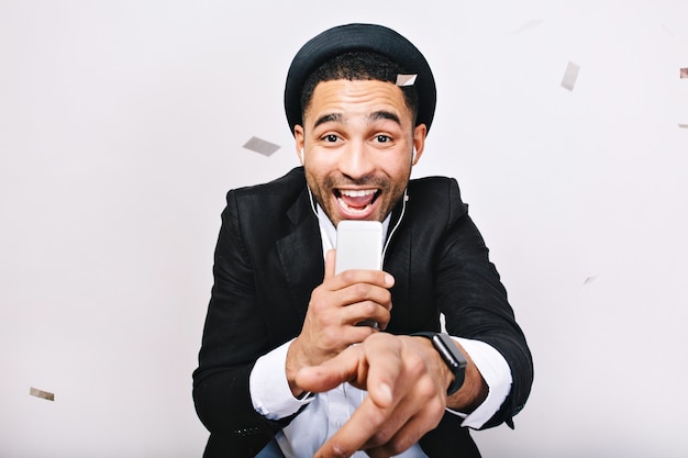 Portrait celebrating karaoke party of excited handsome guy in suit, hat having fun. Fashionable look, cheerful mood, singing, music, enjoying, expressing positivity, happiness.