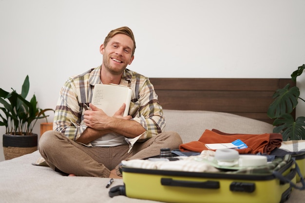 Free Photo portrait of charismatic handsome man tourist looking at notebook getting ready for journey packing