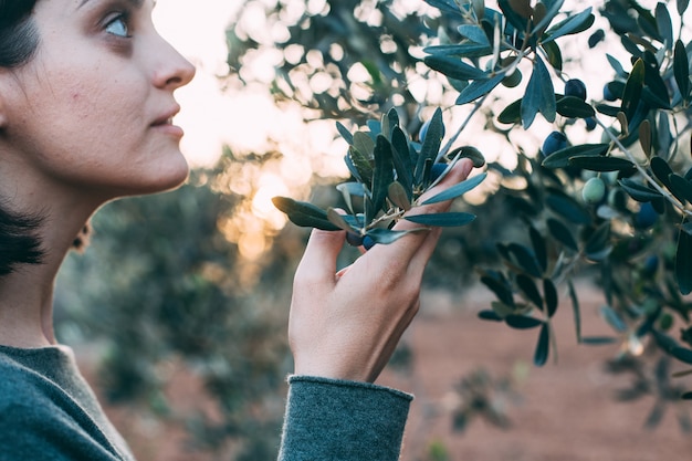 Free photo portrait of charming lady in summer resort outfit posing next to olive tree