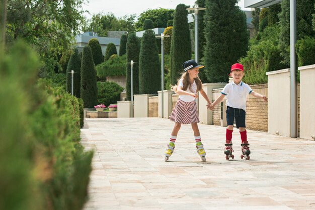 Portrait of a charming teenage couple skating together on roller skates at park. Teen caucasian boy and girl.