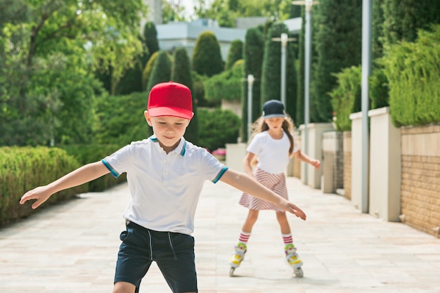 Portrait of a charming teenage couple skating together on roller skates at park. Teen caucasian boy and girl