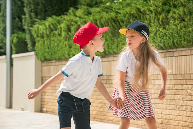 Portrait of a charming teenage couple skating together on roller skates at park.